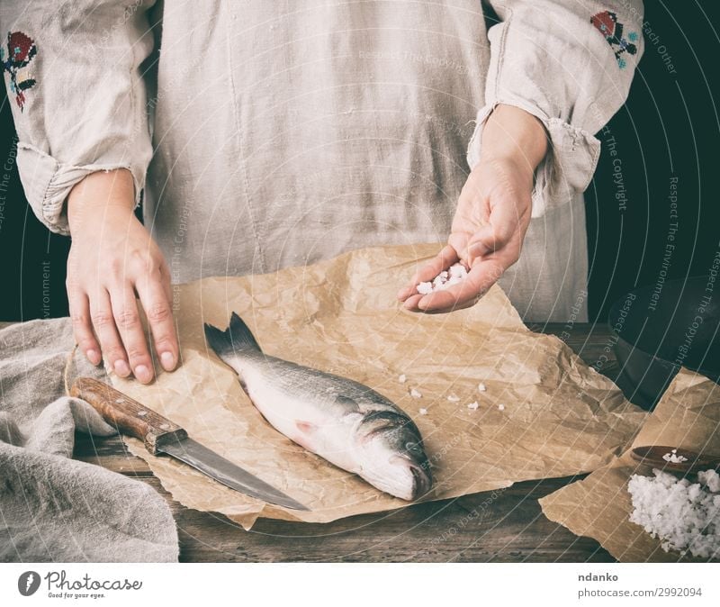 fresh whole sea bass fish lying on brown paper Meat Fish Seafood Herbs and spices Nutrition Ocean Table Kitchen Tool Human being Hand Animal Paper Wood Make