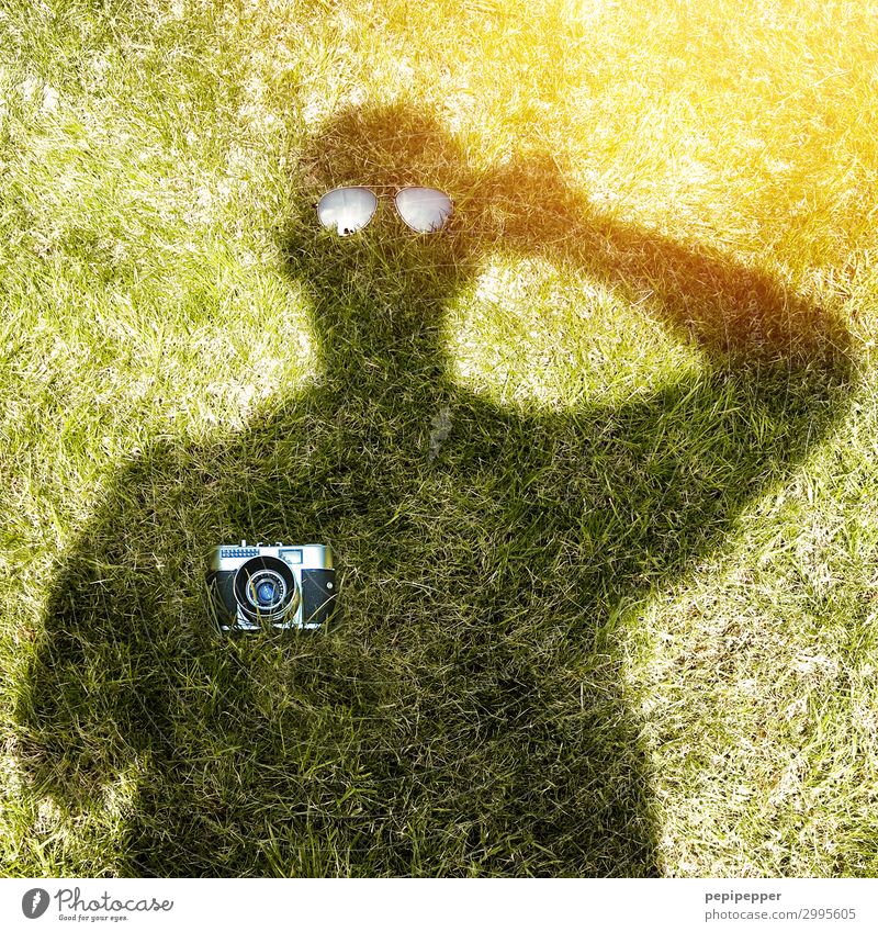 Shadow image of man holding a camera and sunglasses Leisure and hobbies Garden Human being Masculine Body 1 Sunlight Grass Eyeglasses Camera Green Colour photo