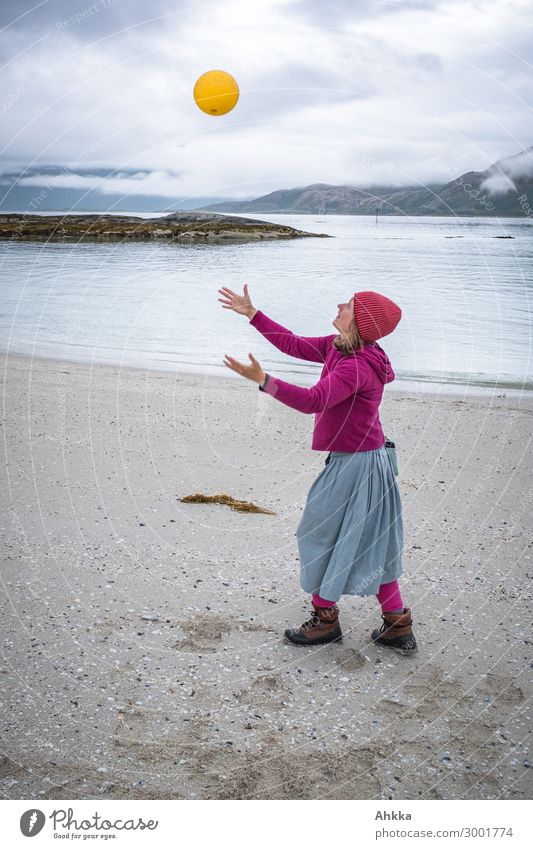 Young woman plays with flotsam and jetsam Joy Playing Education Youth (Young adults) Nature Clouds Bad weather Rain Coast Beach Norway Ball Waste utilization
