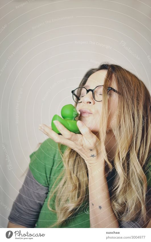 woman kissing a rubber duck (the frog is already gone) Woman hair Wearer of glasses Hand Rubber duck Whimsical Squeak duck Green Desire Frog Hair and hairstyles