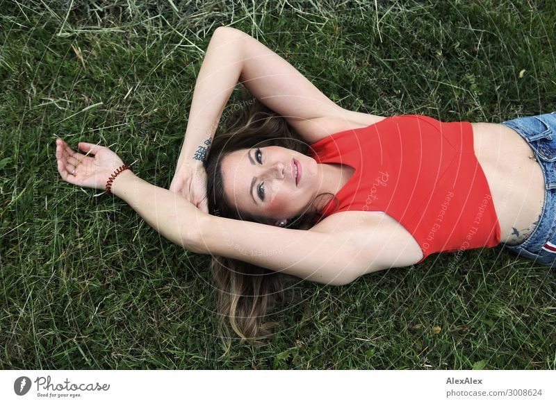 Young woman lies in the grass Lifestyle Happy Beautiful Harmonious Well-being Youth (Young adults) 18 - 30 years Adults Plant Beautiful weather Grass Meadow Top
