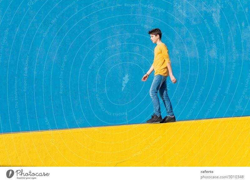 Young boy wearing casual clothes walking against a blue wall in a sunny day Lifestyle Summer Sun Human being Masculine Child Boy (child) Man Adults