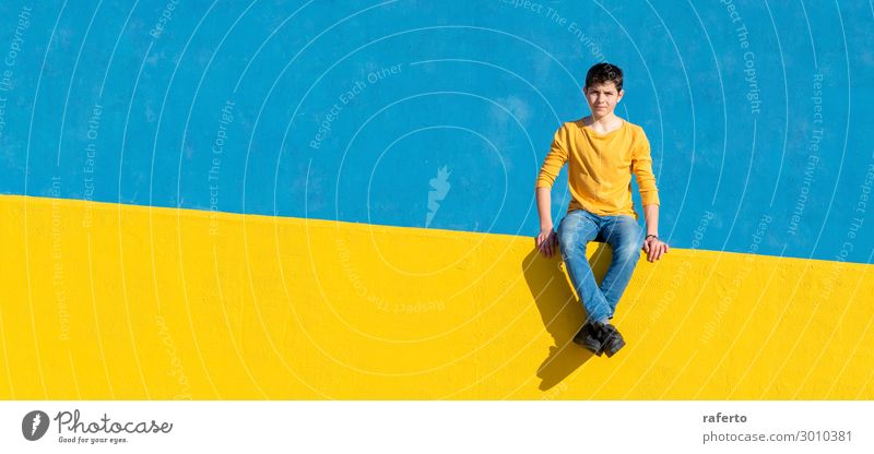 Young boy wearing casual clothes sitting on a yellow fence Lifestyle Relaxation Summer Sun Boy (child) Man Adults Youth (Young adults) Street Fashion Clothing