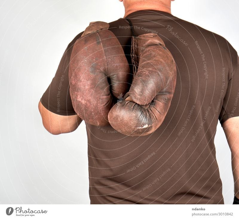 athlete holds a pair of very old vintage boxing gloves Lifestyle Body Sports Sportsperson Success Man Adults Hand Leather Gloves Old Fitness Hang Brown Power