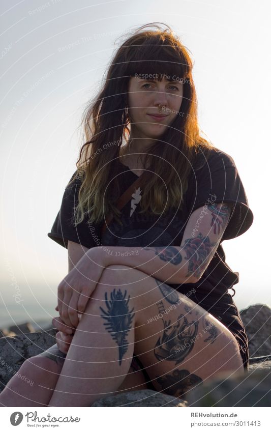 Carina - Young tattooed woman sits on a mountain Woman Tattooed Summer T-shirt Mountain Above Human being Exterior shot Young woman Nature evening light Sit