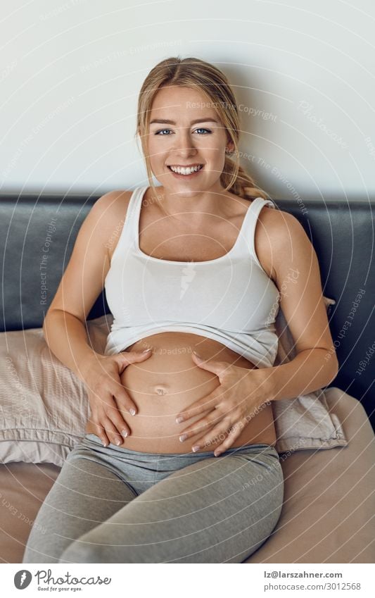 Happy smiling attractive young pregnant woman Woman Adults 1 Human being 18 - 30 years Youth (Young adults) Smiling Love Sit Pregnant pregnancy cradling belly