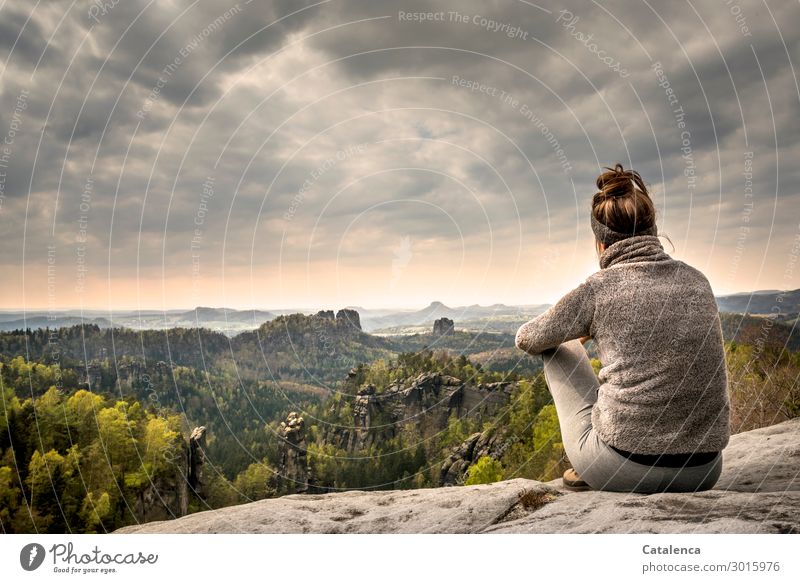 Young woman on a rock in the Elbe Sandstone Mountains looks into the landscape person Sit Observe Horizon Forest rock formation Rock stones Sky Clouds
