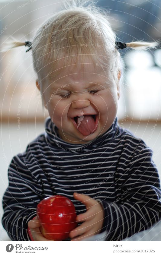 Bite the acid apple. Human being Feminine Child Toddler Infancy Eating apples Grimace Evening portrait Looking Looking into the camera Forward Wink Closed eyes