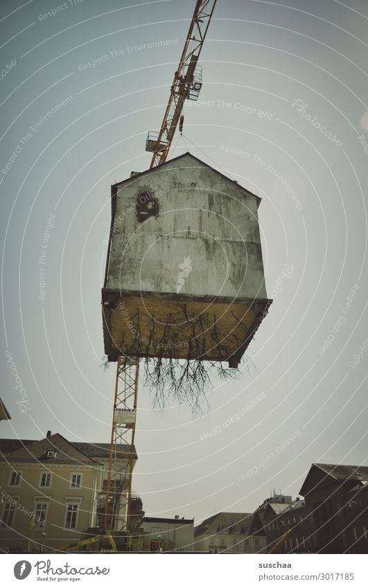 Airy house in the air. House (Residential Structure) Crane Height Town Surrealism Building Hover Tall Run away roots Dismantling Transport Exceptional