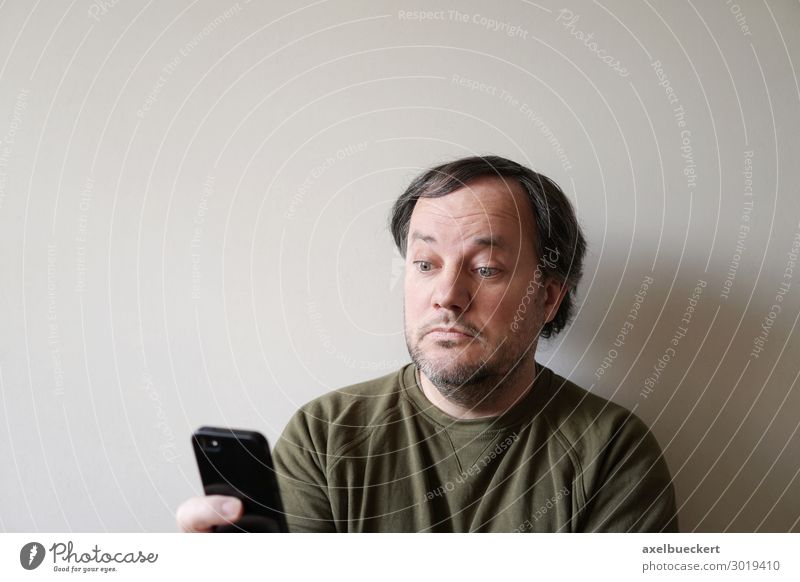 Man looks puzzled at smartphone Lifestyle Telephone Cellphone PDA Technology Entertainment electronics Telecommunications Internet Human being Adults 1