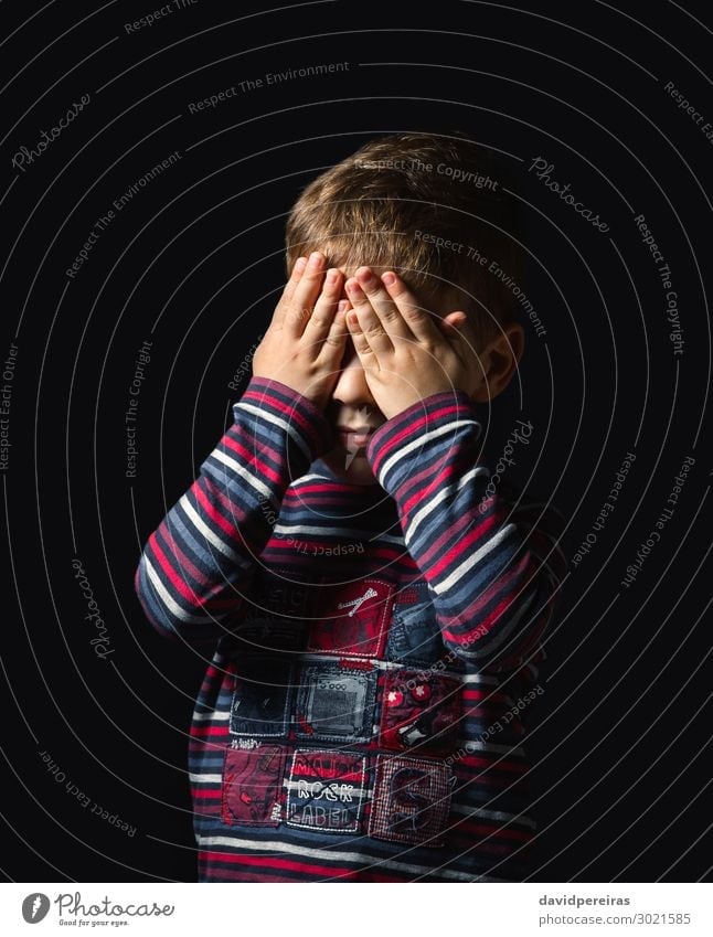 Scared boy covering eyes with hands over black background Face Child Human being Boy (child) Man Adults Infancy Hand Stripe Stand Cry Authentic Dark Small Cute