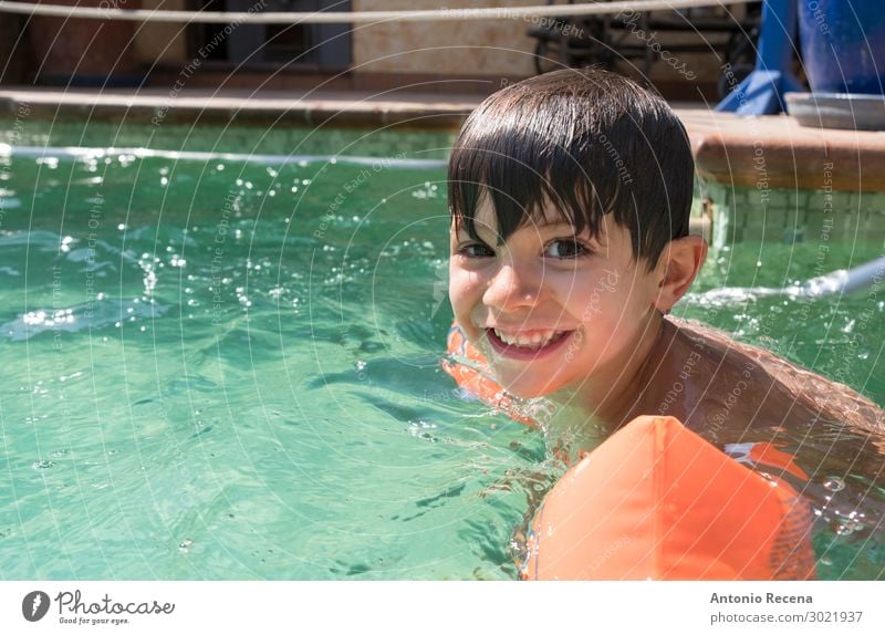 Boy wearing arm floaties in a swimming pool Joy Happy Swimming pool Leisure and hobbies Child Human being Boy (child) Man Adults Infancy Arm Brunette Smiling