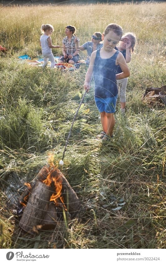 Little boy roasting marshmallow over a campfire Lifestyle Joy Happy Relaxation Vacation & Travel Summer Summer vacation Child Human being Girl Boy (child) Woman