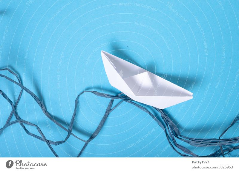 Paper ship on a blue background and blue cord, representing the waves Paper boat Waves Gale churned Agitated Stress Adventure Movement Chaos Tourism Logistics