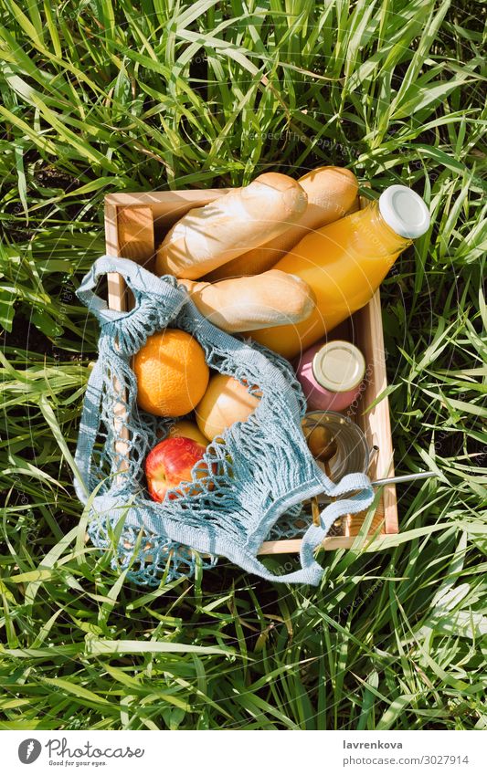 Various fruits and cold beverages in a wooden box Picnic eco bags Baguette Bread Diet Beverage Glass Bottle Milkshake Juice Orange Apple Fruit Vegan diet
