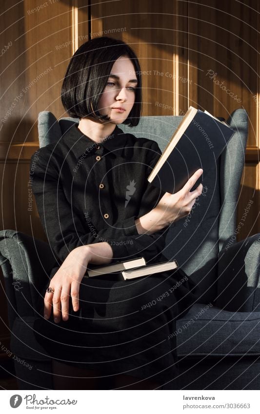 Woman sitting in a chair and reading books Book Chair Cozy Dress Faceless Fingers Hand Leisure and hobbies Hold Home hygge Lifestyle Portrait photograph Reading