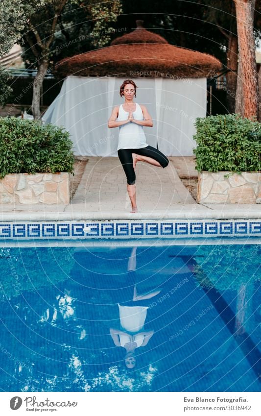 woman doing yoga by swimming pool. Yoga and mindfulness Lifestyle Beautiful Body Relaxation Calm Meditation Spa Swimming pool Leisure and hobbies