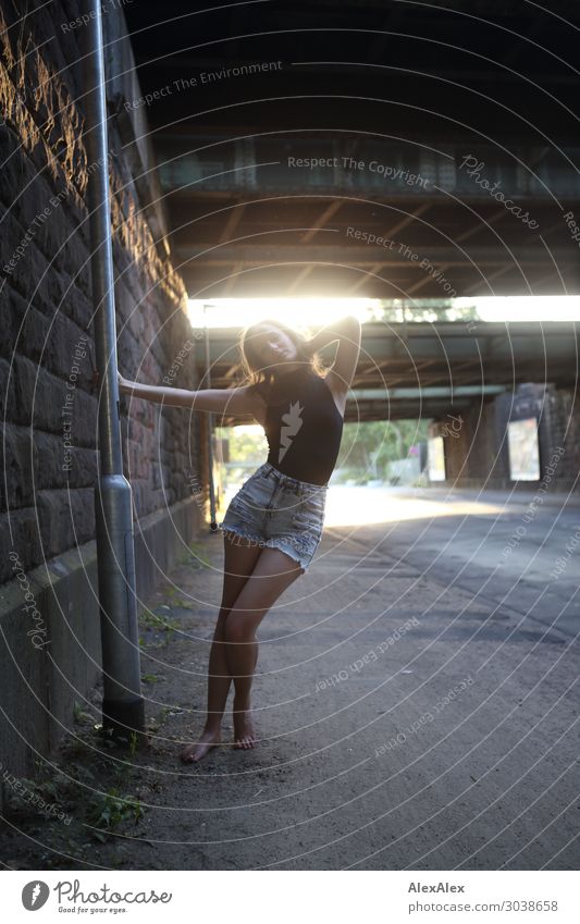 Young woman swinging at a lantern in the backlight under a bridge at a street Lifestyle Style Joy pretty Lamp post Bridge Wall (barrier) Street