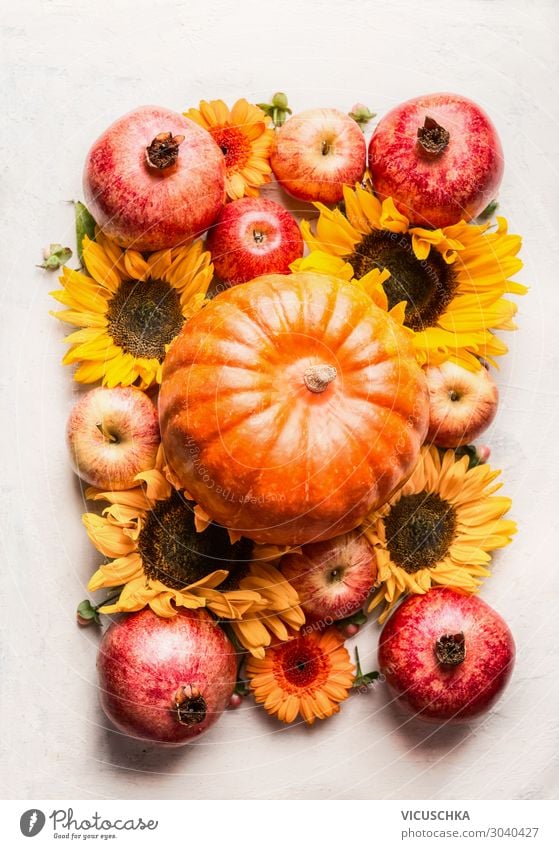 Pumpkin with apples, flowers, pomegranate and sunflowers on white table, top view. Autumn or late summer layout composing. Thanksgiving  arrangement pumpkin
