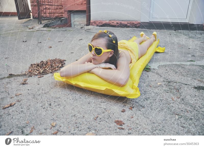 girl on a yellow air mattress in a grey backyard Summer Autumn flaked Longing Vacation & Travel Swimming & Bathing Air mattress Yellow Sunglasses Child