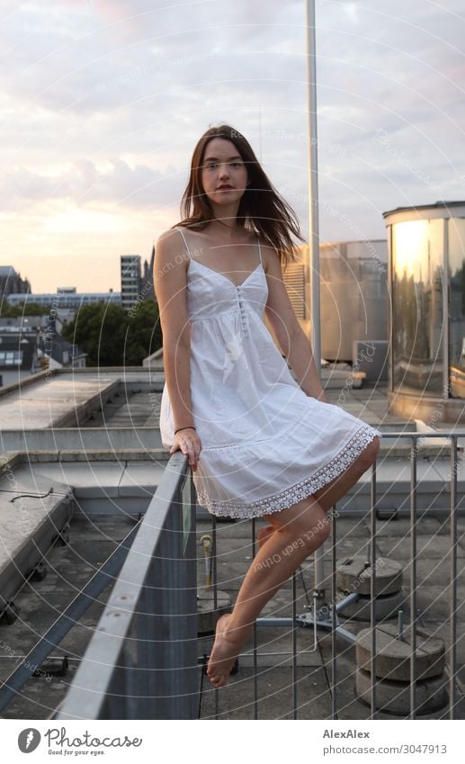 Young woman sitting on roof terrace railing Lifestyle Style Joy Beautiful Roof Roof terrace Handrail Town Lightning rod Youth (Young adults) Legs 18 - 30 years
