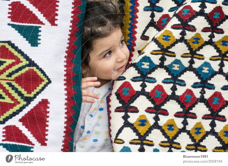 Little girl close up portrait between kilims with traditional folk geometric patterns Luxury Design Knit Child 1 - 3 years Art Culture Touch Shopping Looking