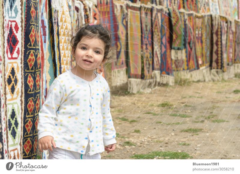 Little girl portrait in front of colorful kilims with geometric patterns Lifestyle Luxury Beautiful Knit Tourism Child Trade Business Human being Girl