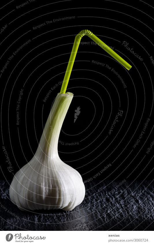Cheers - Garlic on slate with a green drinking straw against a black background Garlic bulb Food Herbs and spices Straw Nutrition Organic produce Beverage