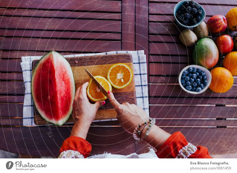 young woman preparing a healthy recipe of diverse fruits, watermelon, orange and blackberries. Using a mixer. Homemade, indoors, healthy lifestyle