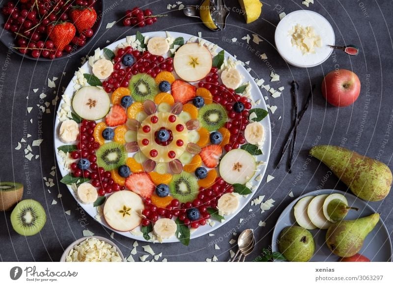 Colorful fruit plate arranged as a flower pattern on dark plate with delicious cream and ingredients Fruit salad Food Dessert Chocolate Vanilla pod Strawberry