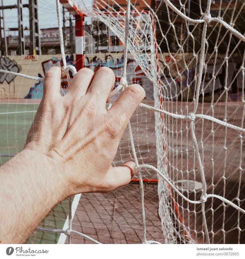 hand grabbing a soccer rope net in the field Hand Man Human being Fingers Body Arm Rope Net Internet Sports equipment tied tangled Street Exterior shot