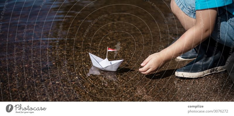 Small boy puts small paper ship in water Joy Happy Healthy Alternative medicine Relaxation Calm Swimming & Bathing Playing Handicraft Model-making
