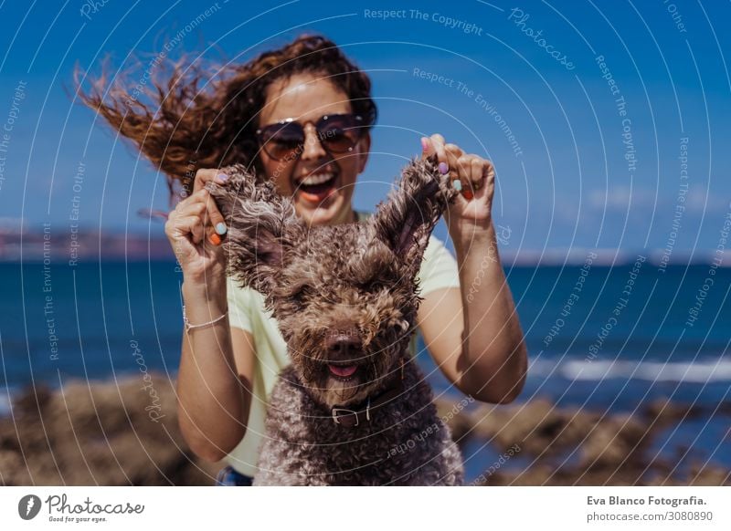 young woman and her cute spanish water dog outdoors enjoying together on a sunny and windy day. Summertime, love for animals and holidays concept Playing Dog