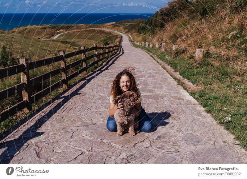 young woman and her cute spanish water dog outdoors enjoying together on a sunny and windy day. Summertime, love for animals and holidays concept Playing Dog