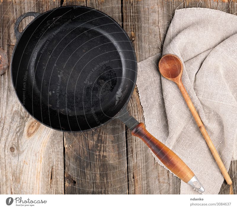empty black round frying pan with handle and spoon Pan Spoon Table Kitchen Tool Wood Metal Old Above Clean Brown Gray Black background board Cast cooking