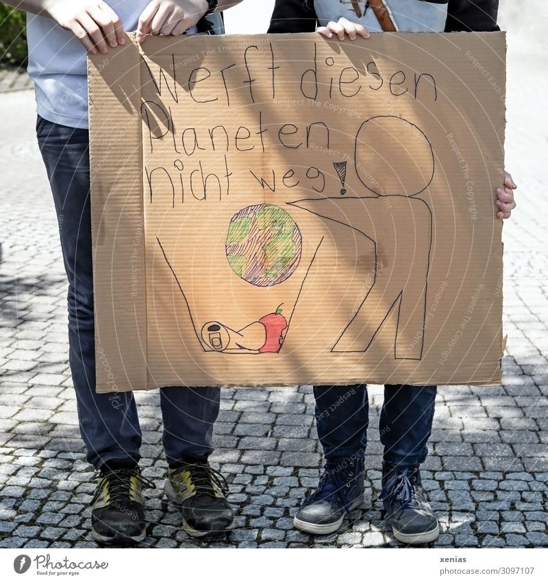 valuable / Do not throw away this planet! Two teenagers are standing on the street holding painted cardboard in their hands for fridays for future - Demonstration