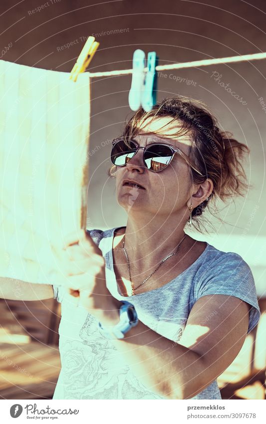 Woman hanging laundered bed linen on clothesline Summer Adults 1 Human being 45 - 60 years Clothing Sunglasses Hang Authentic Wet Clean Clothesline Hanging