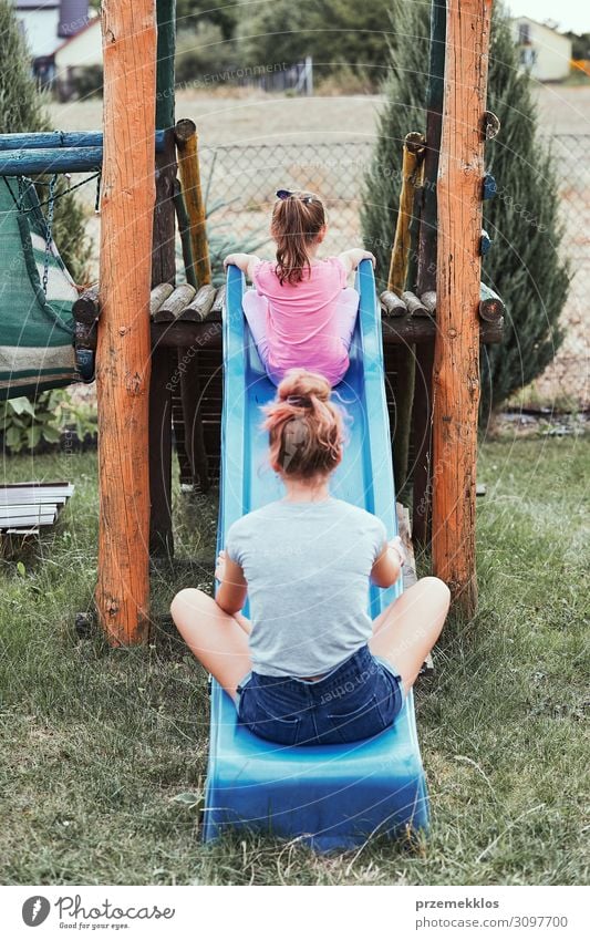 Sisters having fun on a slide together Lifestyle Joy Summer Summer vacation Garden Child Family & Relations 2 Human being 3 - 8 years Infancy 13 - 18 years