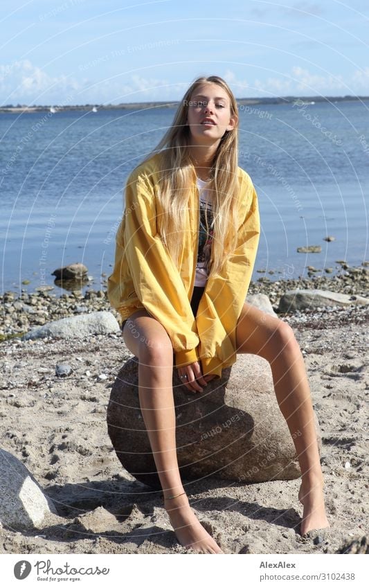 Young woman with yellow jacket sits on the beach Lifestyle Joy pretty Summer Sun Sunbathing Beach Ocean Youth (Young adults) Legs 18 - 30 years Adults