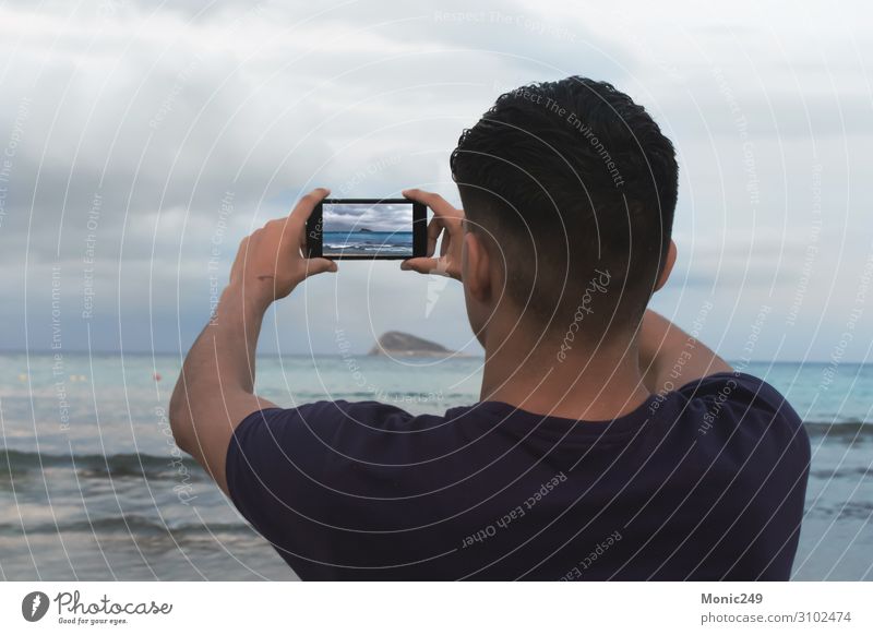 Brunette boy facing the sea, taking a picture with a smartphone Relaxation Vacation & Travel Tourism Beach Ocean Waves Winter To talk Telephone Cellphone