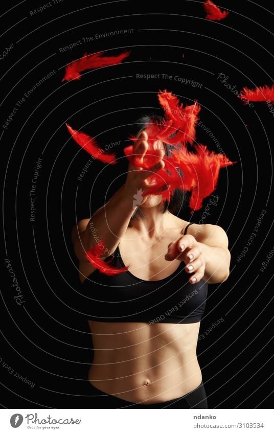 beautiful athletic girl in black clothes throws up red feathers - a Royalty  Free Stock Photo from Photocase