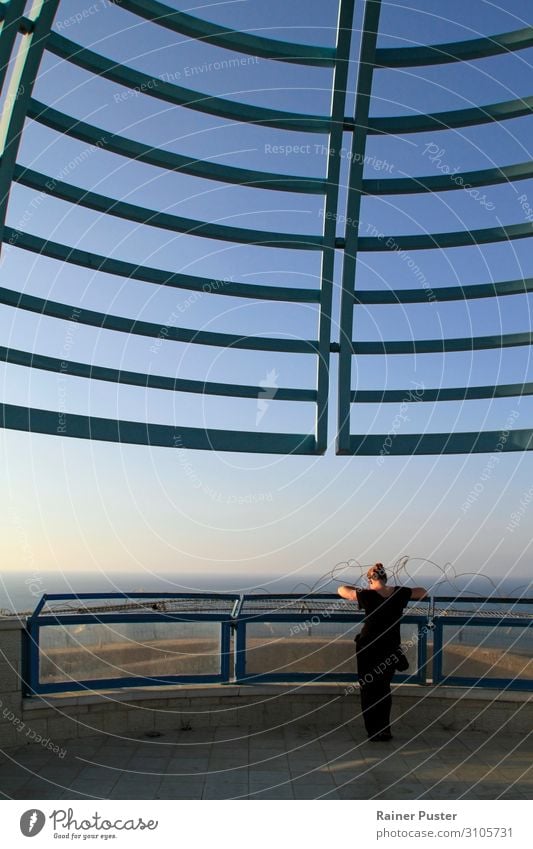 A woman stands at a lookout over the sea under a sunny sky Feminine Woman Adults Cloudless sky Ocean Tel Aviv Israel Vantage point Reading Colour photo
