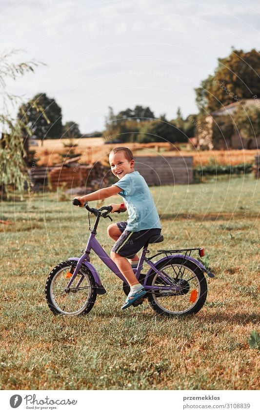 Happy smiling boy riding a bike Lifestyle Joy Relaxation Leisure and hobbies Playing Summer Garden Child School Human being Boy (child) Infancy 1 30 - 45 years