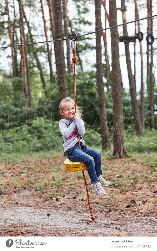 Happy girl riding on the zip line in rope park Joy Playing Vacation & Travel Adventure Summer Child Rope Human being Infancy Park Forest Playground Line Sit