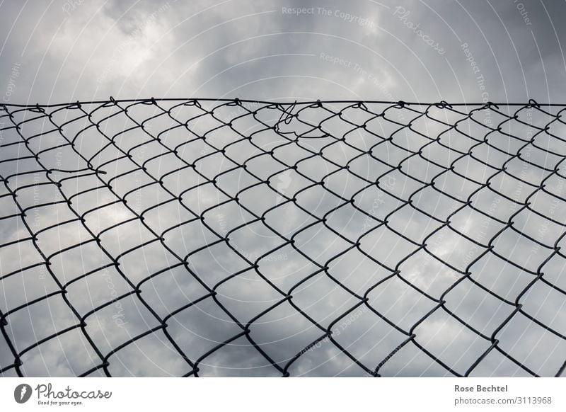 View upwards Metal Sadness Loneliness Fence Wire netting fence Border border fence Dark clouds Upward Subdued colour Exterior shot Copy Space top