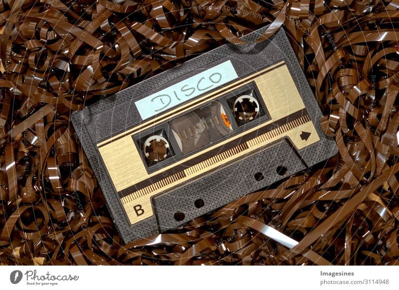 old audio technology, compact music cassette with text - disco, on a large amount of magnetic tape. Magnetic tapes background, realistic retro design
