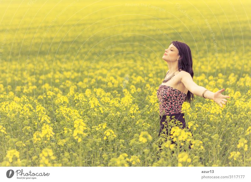 Beautiful young woman in summer on yellow meadow from rape to horizon. Pretty girl with zest for life enjoys the sunshine break and life. Rest and recharge energy from time stress in environment and nature idyll. Eyes closed.