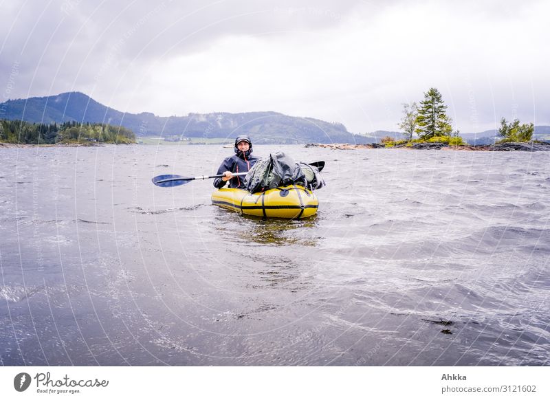 Paddler in bad weather with wind and rain and wild clouds on a lake in the mountains Gale Headwind Kayak Boating trip Rain Waves Fight Good mood Wet Wild