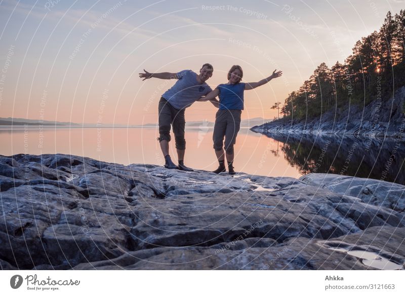 Young couple waving happily on a calm lake in the evening Couple Relationship Affection Happy Together Harmonious Lake Nature Evening Calm Rock Scandinavia