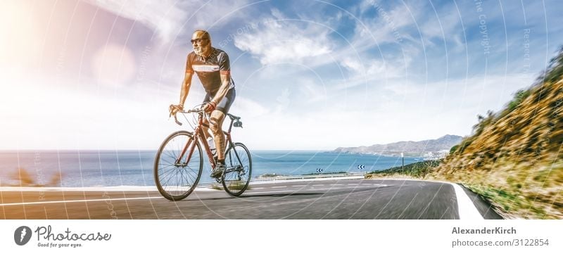 Mature Adult on a racing bike climbing the hill at mediterranean sea landscape coastal road Vacation & Travel Summer Beach Sports Human being Nature